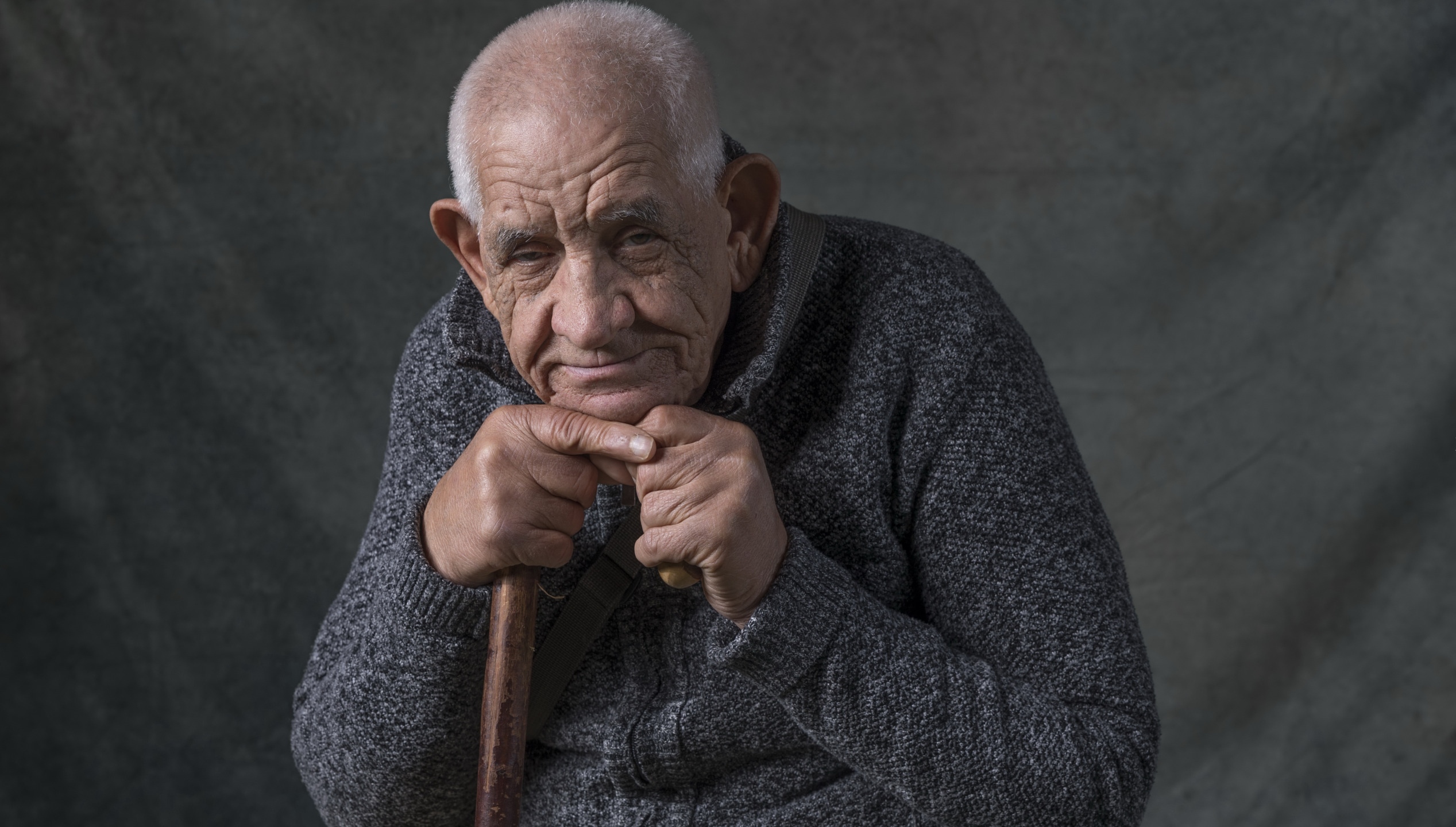 Zastaki.com - Пожилой мужчина в теплом свитере на сером фоне 