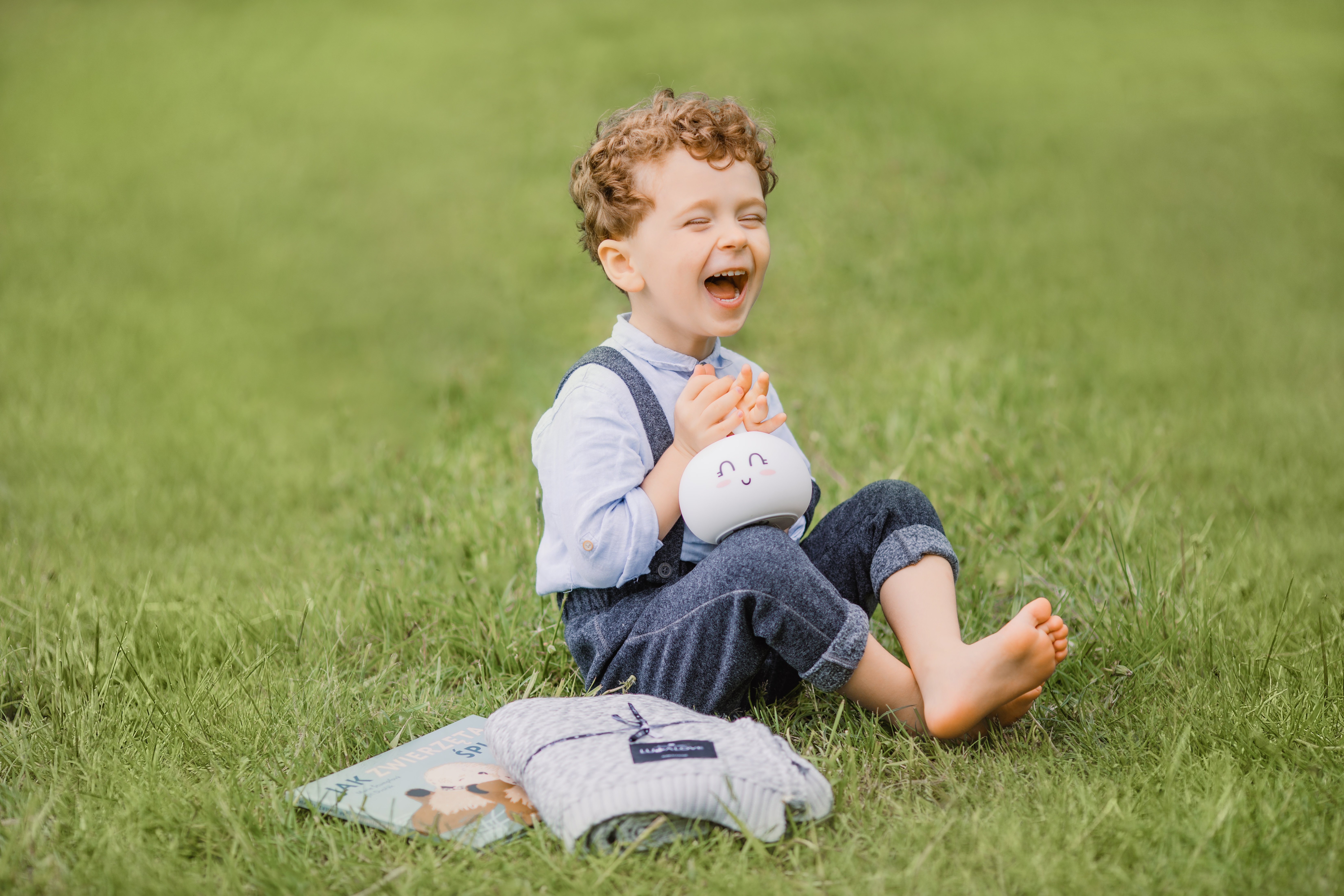 Мы сидим на веселе делать. Мальчик улыбается. Ребенок. Мальчик сидит на траве. Мальчик смеется.