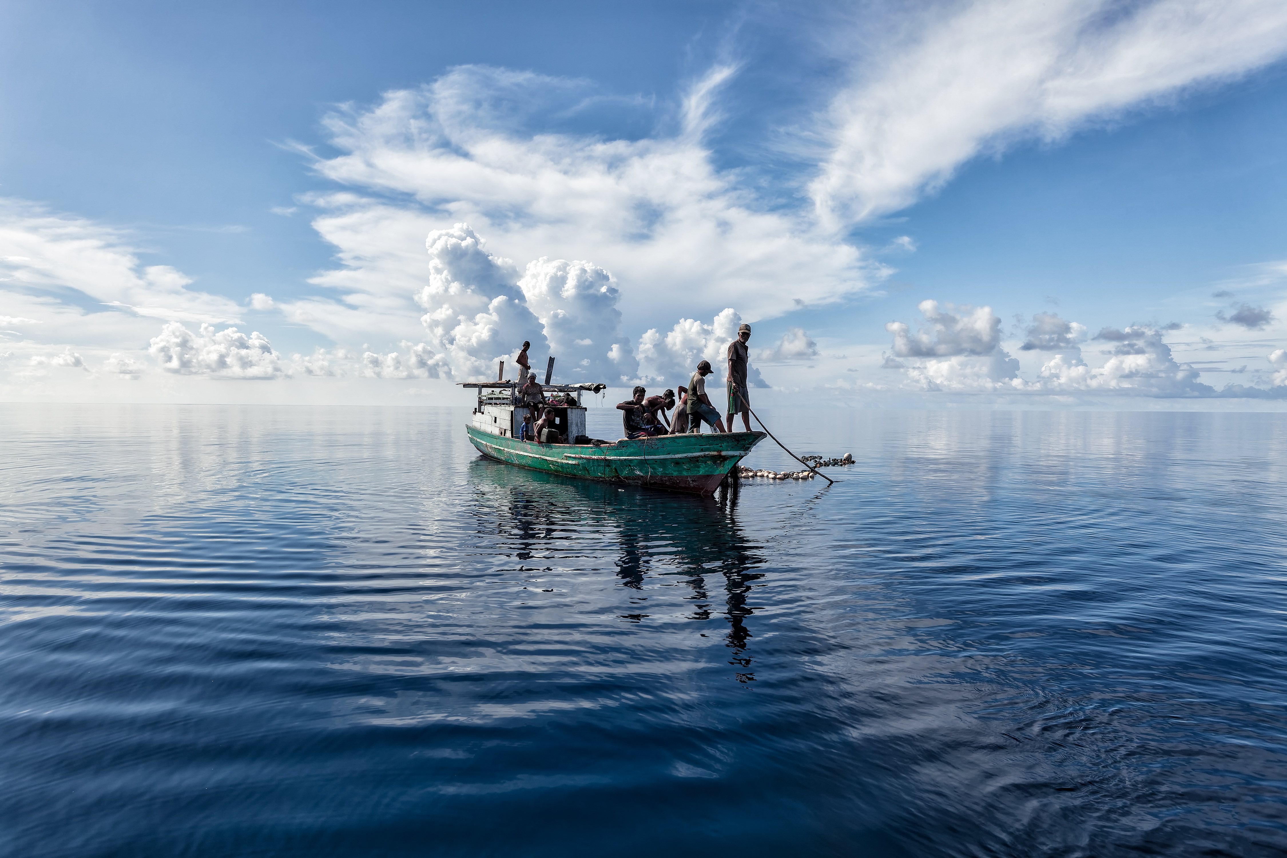 Zastaki.com - Лодка с рыбаками в море с белыми облаками 
