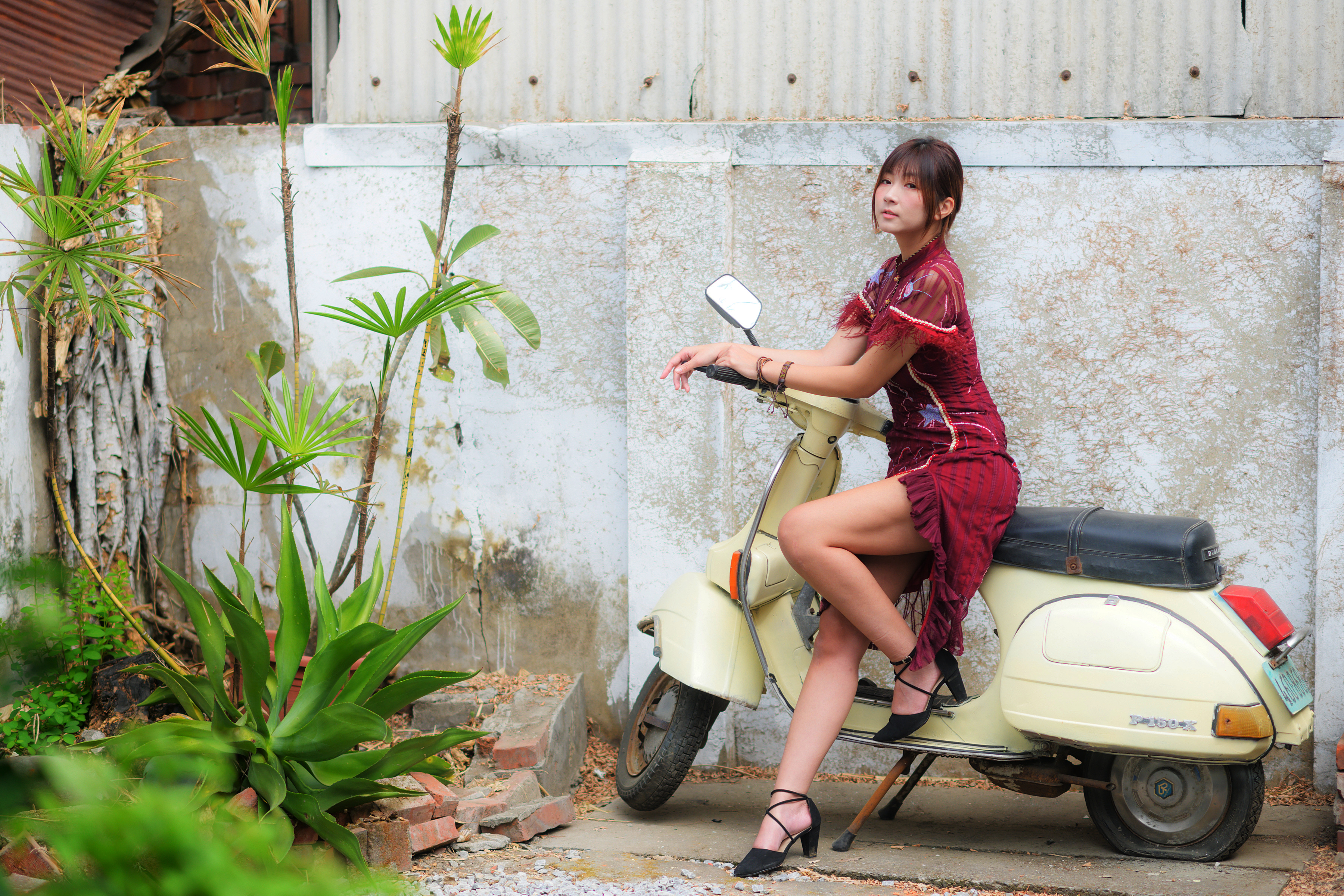 Zastaki.com - Девушка азиатка сидит на скутере у стены