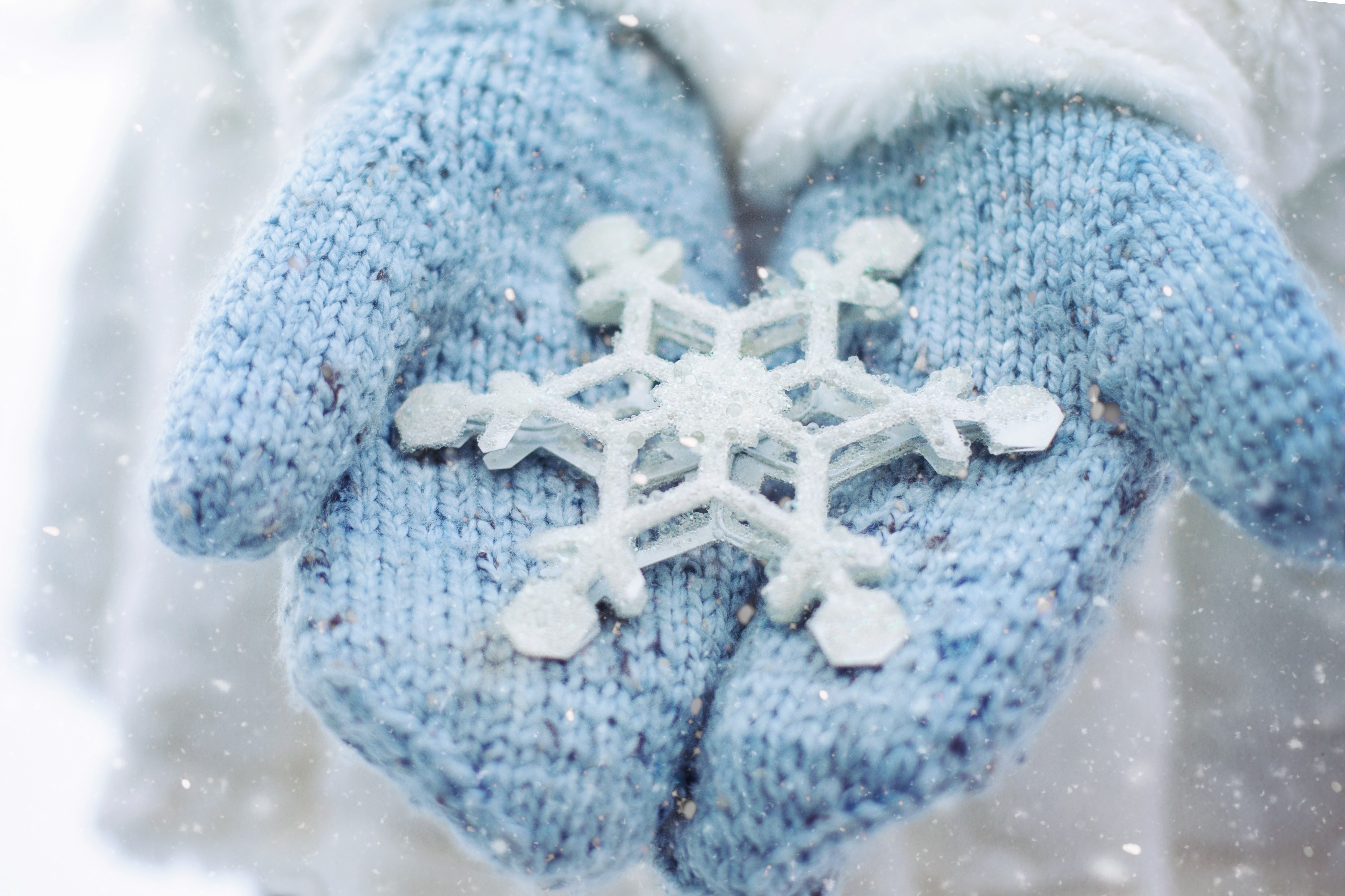 Blue mittens on hands with a white snowflake